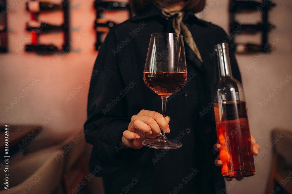 Female sommelier swirling red wine in glass on cellar background being in cellar. Wine expert exam to study different wine. Female sommelier swirling red wine in glass on cellar background being in cellar. Wine expert exam to study different wine.
