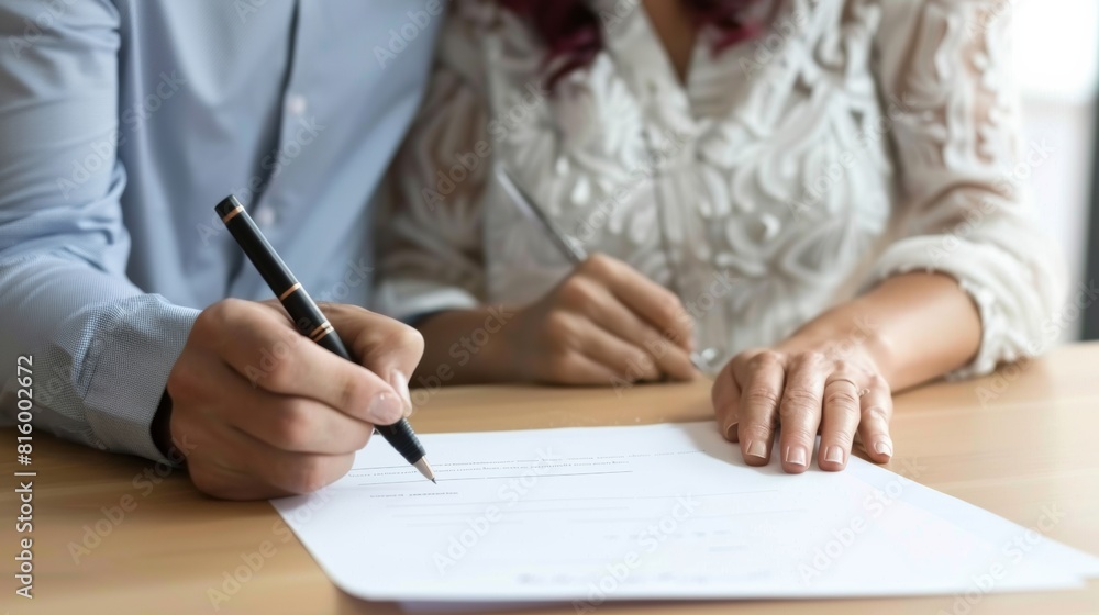 Two professionals in a meeting, one preparing to sign a document, focus on hands and pen, business agreement concept. Two professionals in a meeting, one preparing to sign a document, focus on hands and pen, business agreement concept.