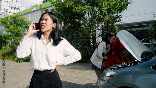 Frustrated woman on call, schoolgirl and mechanic examine car engine, against greenery backdrop. Concept of taking care of car insurance after accident