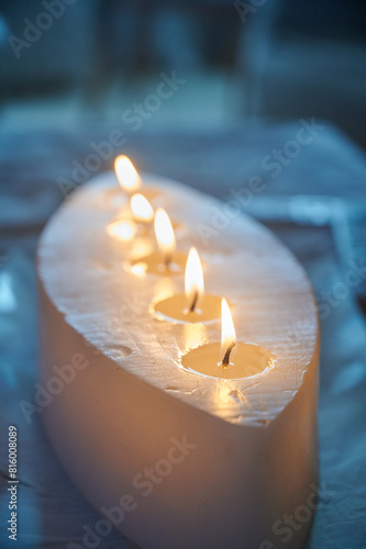 Natural wax candle with several wicks lit inside the home to create a cozy atmosphere. Decorative elements in the home.