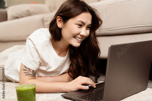Happy Young Woman Using Laptop At Home, Smiling Asian Female Enjoying Surfing The Internet Or Working Remotely, Comfortable Living Room Setup