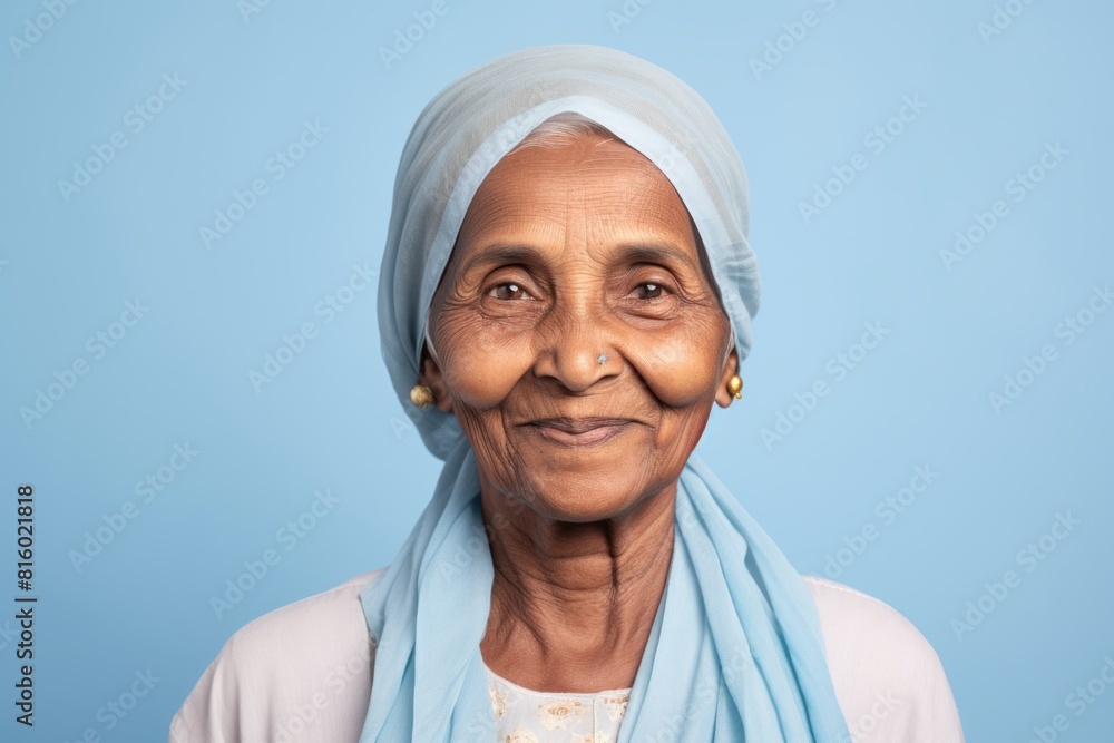 Portrait of a content indian elderly woman in her 90s smiling at the camera isolated on soft blue background Portrait of a content indian elderly woman in her 90s smiling at the camera isolated on soft blue background