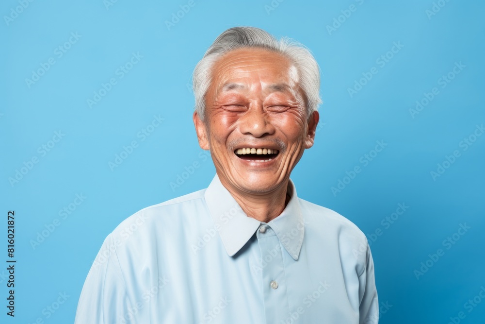 Portrait of a cheerful asian elderly man in his 90s laughing isolated on soft blue background Portrait of a cheerful asian elderly man in his 90s laughing isolated on soft blue background