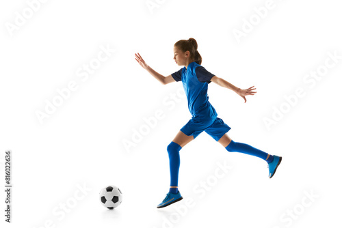 Teenager in motion, girl in blue uniform dribbling ball, practicing football skills isolated on white studio background. Concept of sport, active and healthy lifestyle, childhood, school, hobby