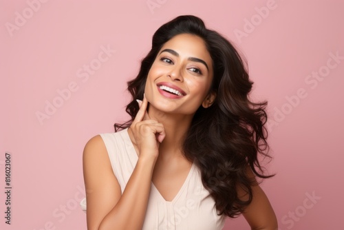 Portrait of a joyful indian woman in her 30s showing a thumb up isolated on soft pink background