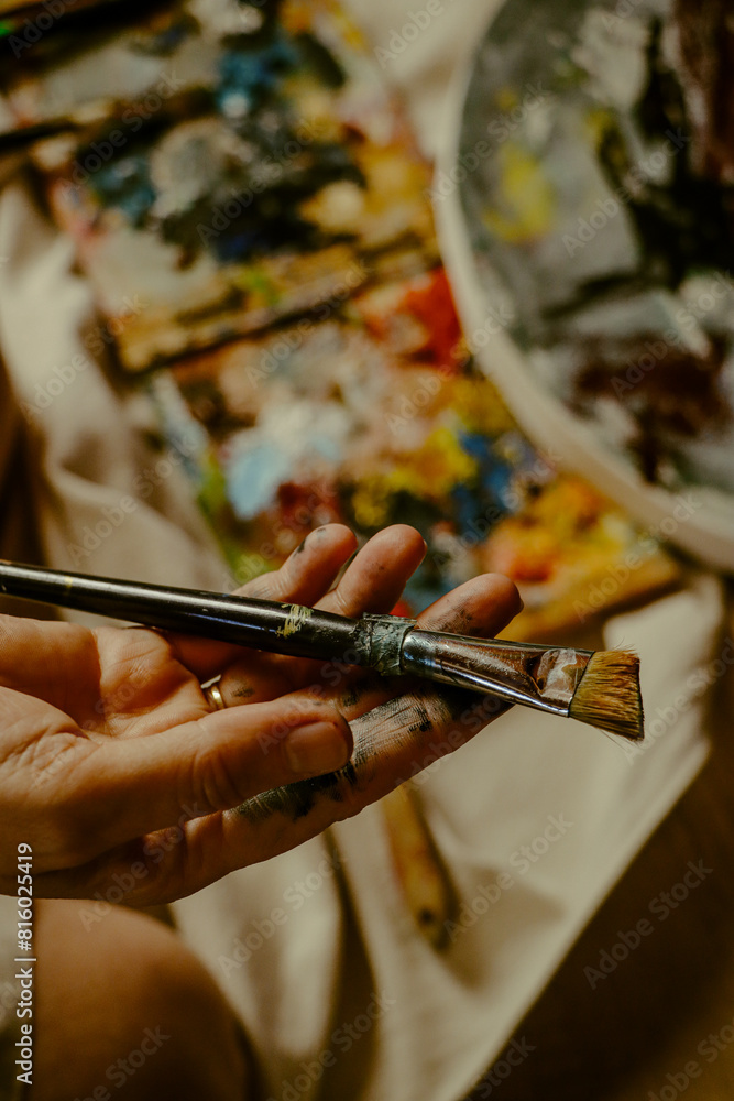 Woman's hand carrying paint brush on canvas