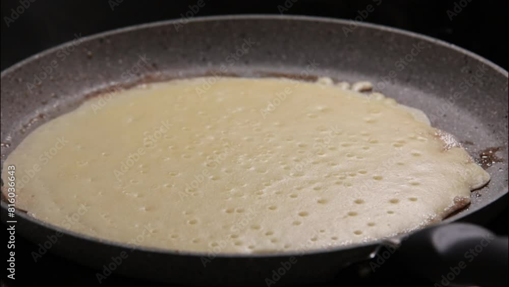 woman pouring pancake batter into a frying pan as crepes are fried, with cooking smoke rising from the pancake. This close-up stock video woman pouring pancake batter into a frying pan as crepes are fried, with cooking smoke rising from the pancake. This close-up stock video