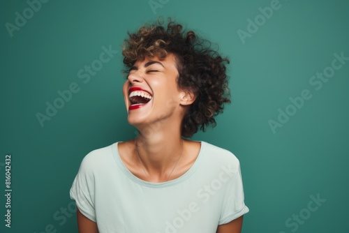 Portrait of a content woman in her 30s laughing in front of soft green background