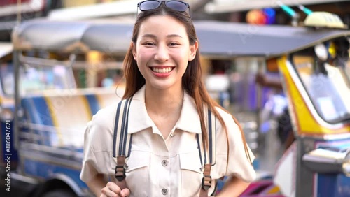 Young Asian woman smiling at camera while traveling backpacker in Khaosan Road outdoor market in Bangkok, Thailand. High quality 4k footage photo