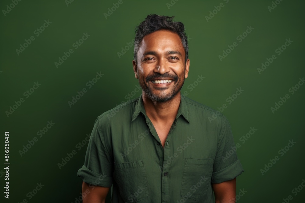 Portrait of a content indian man in his 30s smiling at the camera isolated in soft green background Portrait of a content indian man in his 30s smiling at the camera isolated in soft green background