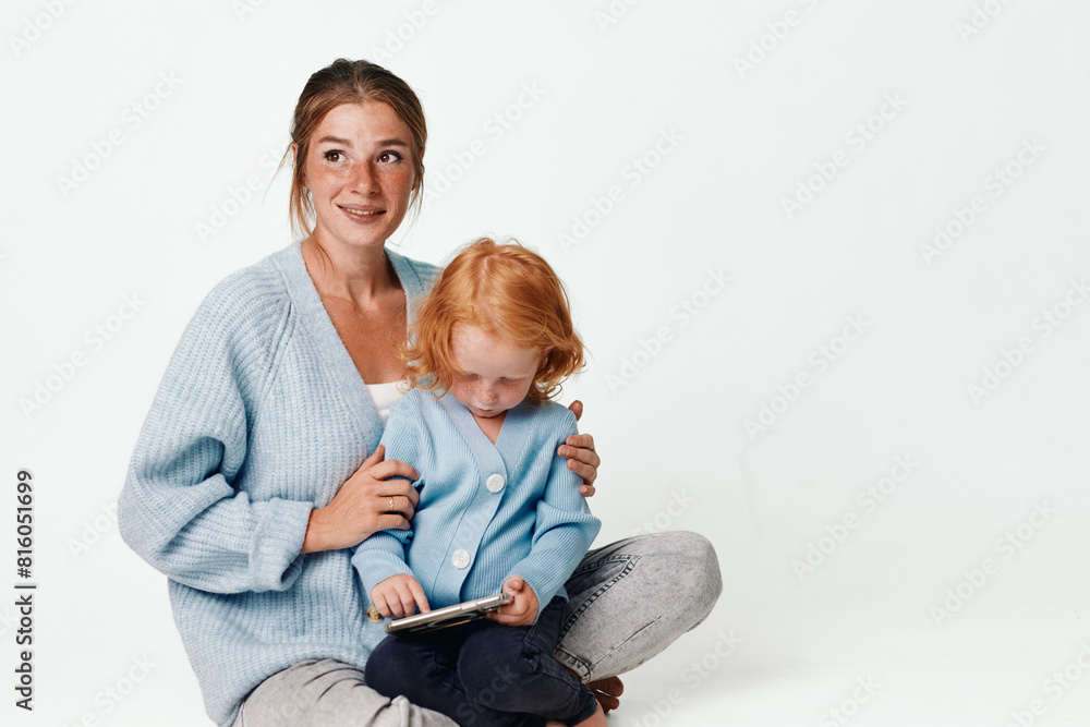 Mother and child using tablet computer together on floor in home setting for educational and entertainment purposes