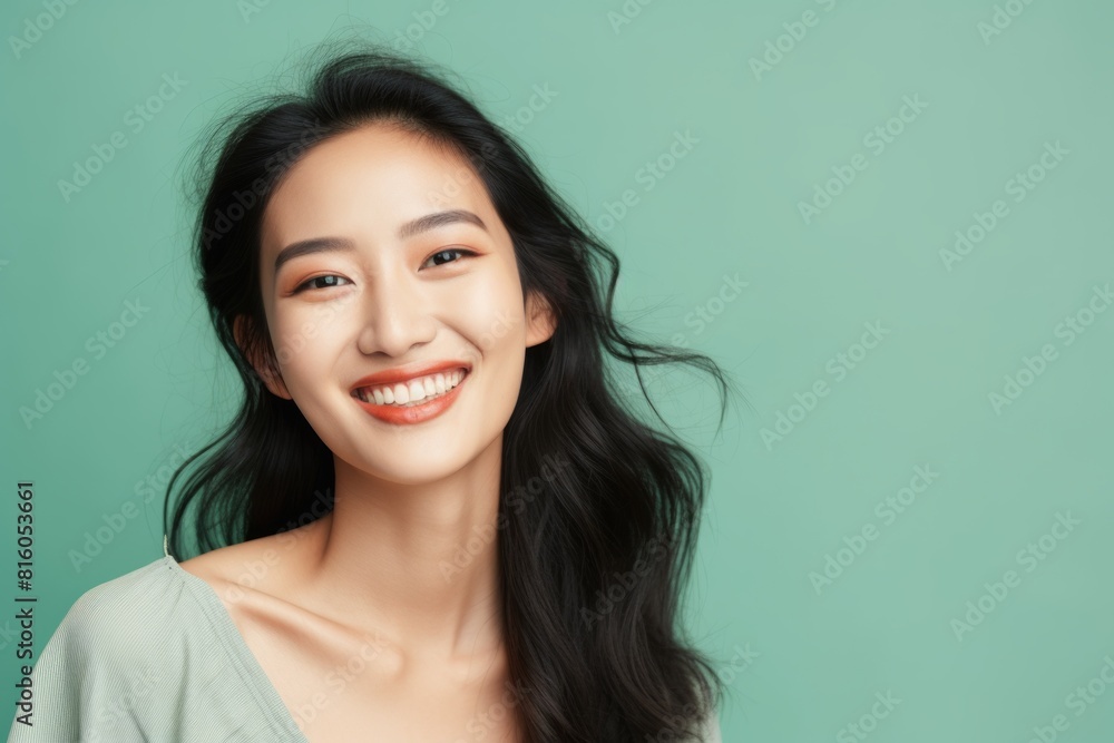 Portrait of a tender asian woman in her 20s smiling at the camera in soft green background Portrait of a tender asian woman in her 20s smiling at the camera in soft green background