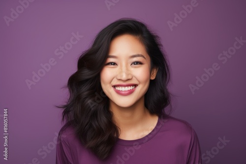 Portrait of a grinning asian woman in her 20s smiling at the camera on soft purple background