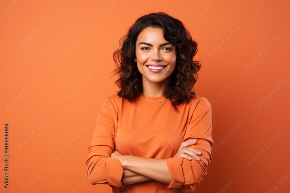 Portrait of a happy woman in her 30s with arms crossed isolated in soft orange background Portrait of a happy woman in her 30s with arms crossed isolated in soft orange background