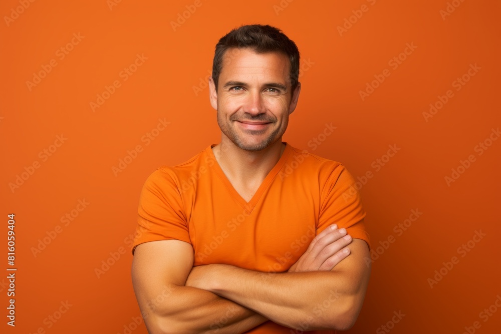 Portrait of a joyful man in his 30s with arms crossed isolated in soft orange background Portrait of a joyful man in his 30s with arms crossed isolated in soft orange background