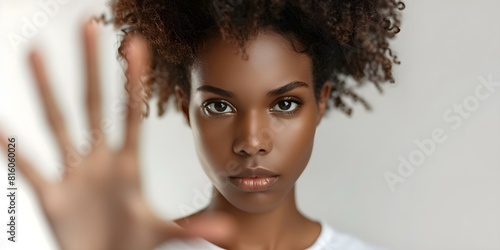 Anxious Black woman in white shirt shows refusal with stop hand gesture. Concept Portrait Photography, Body Language, Emotional Expression photo