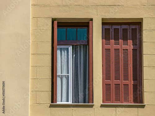 Two windows with brown shutters  one open and the other closed. Some space for text and logo.