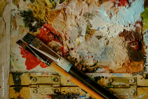 Used brushes on an artist's palette of colorful oil paint