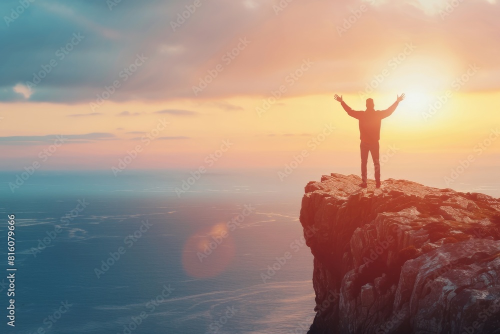 Silhouette of man standing on top mountain with arms raised up at ...