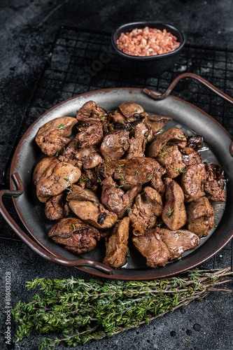 Fried chicken liver with onions and herbs. Black background. Top view