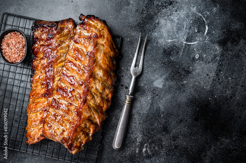 BBQ grilled pork spare ribs on a rack. Black background. Top view. Copy space