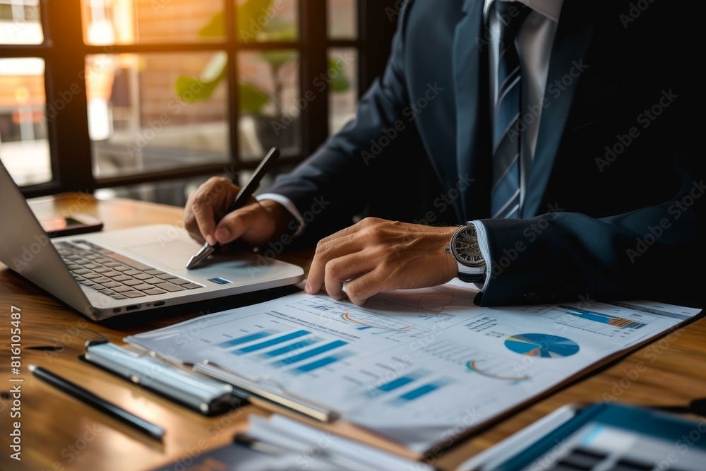 Professional businessman using technology to analyze financial reports and charts in his busy office workspace environment Professional businessman using technology to analyze financial reports and charts in his busy office workspace environment