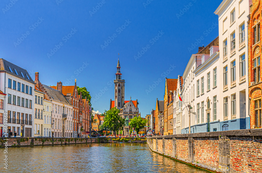 Naklejka premium Bruges cityscape, Spiegelrei water canal, Poortersloge Burghers' Lodge tower, Jan Van Eyck statue, medieval houses on embankment, Brugge old town, Bruges city historic center, Flemish Region, Belgium