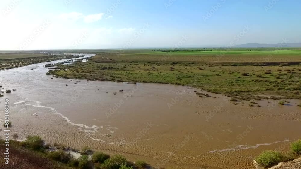 Aerial view of a scenic shot of a flowing river passing through a lush green landscape with an asphalt road running alongside. Aerial view of a scenic shot of a flowing river passing through a lush green landscape with an asphalt road running alongside.
