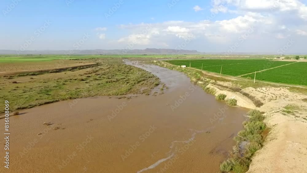 Aerial wide shot of a green landscape with mountains in the distance and a flowing river passing through the terrain. Aerial wide shot of a green landscape with mountains in the distance and a flowing river passing through the terrain.