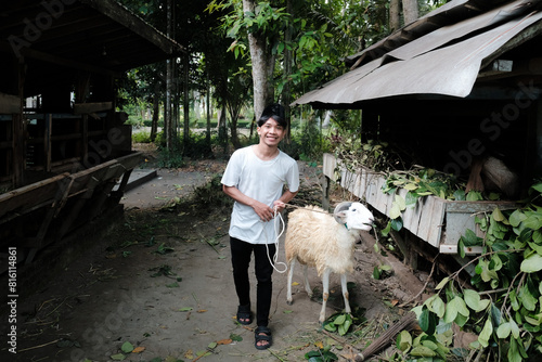 happy man carrying a goat on the farm. eid al adha concept