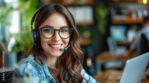 portrait of a smiling Caucasian young woman of age in headphones, headset, customer service employee while in the office photo