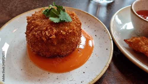 Vegetarian jalapeno ball on plate in resturant with fresh green and sauce