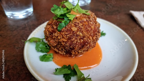 Vegetarian jalapeno ball on plate in resturant with fresh green and sauce