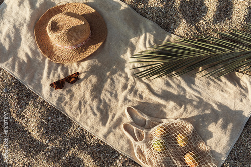 Straw hat, sunglasses, towel, bag on beach sand background. Aesthetic lifestyle, summer vacation concept. Sunbathing, beach party, picnic on summer holiday. Travel fashionable blog, social media.