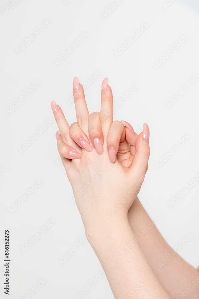 Close-up side view of elegant female hands holding each other against grey background. Soft focus. Femininity and sensuality. Beauty and body care. Relationship bonds. Self expression theme. Close-up side view of elegant female hands holding each other against grey background. Soft focus. Femininity and sensuality. Beauty and body care. Relationship bonds. Self expression theme.
