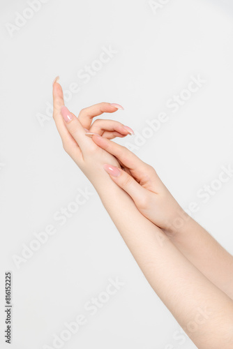 Close-up side view of elegant female hands touching each other during dance against grey background. Soft focus. Femininity and sensuality. Beauty and body care. Self expression theme.