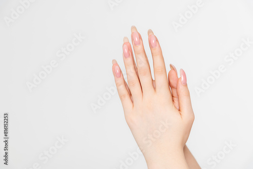 Close-up side view of elegant female hands holding each other in praying gesture against grey background. Soft focus. Spirituality and religious occupation theme.