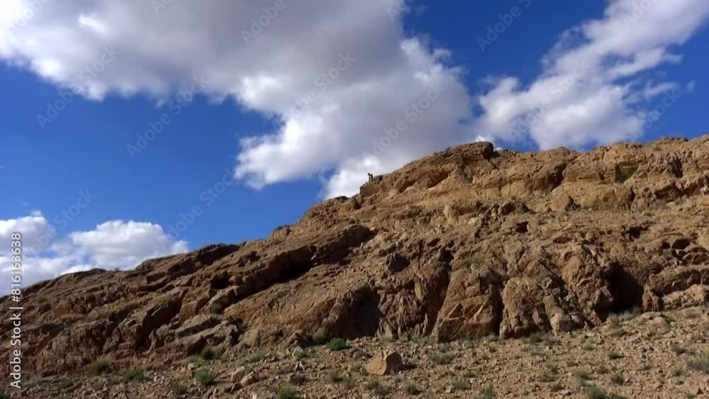 Dynamic beauty of fluffy white clouds moving swiftly against the backdrop of a serene blue sky, as a daring tourist scales rugged. Dynamic beauty of fluffy white clouds moving swiftly against the backdrop of a serene blue sky, as a daring tourist scales rugged.