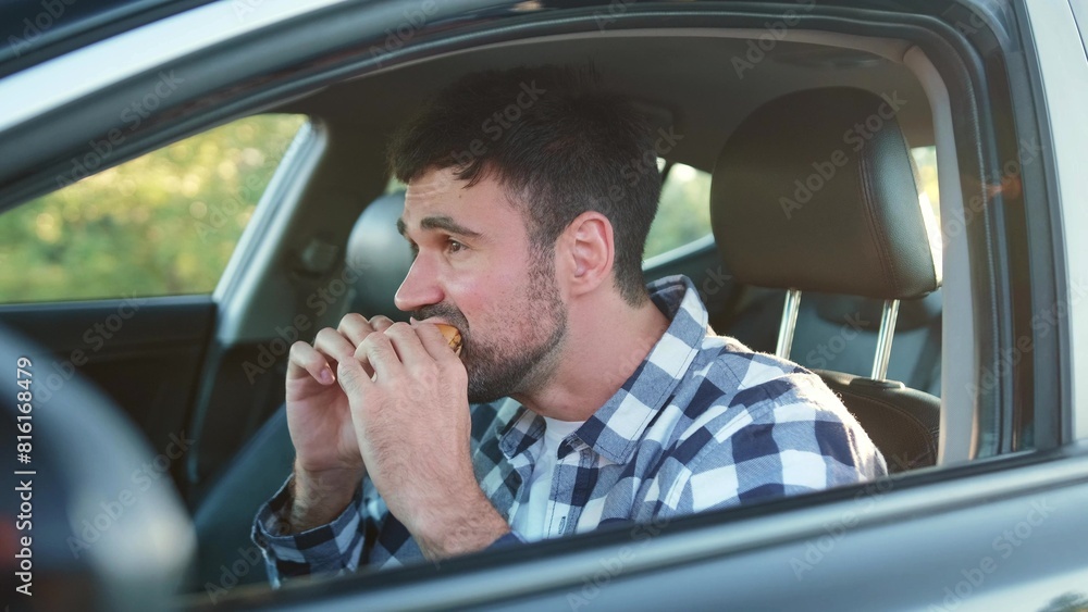 Hungry male driver eating snack in the car. Transport, food, lifestyle, people concept. Hungry male driver eating snack in the car. Transport, food, lifestyle, people concept.