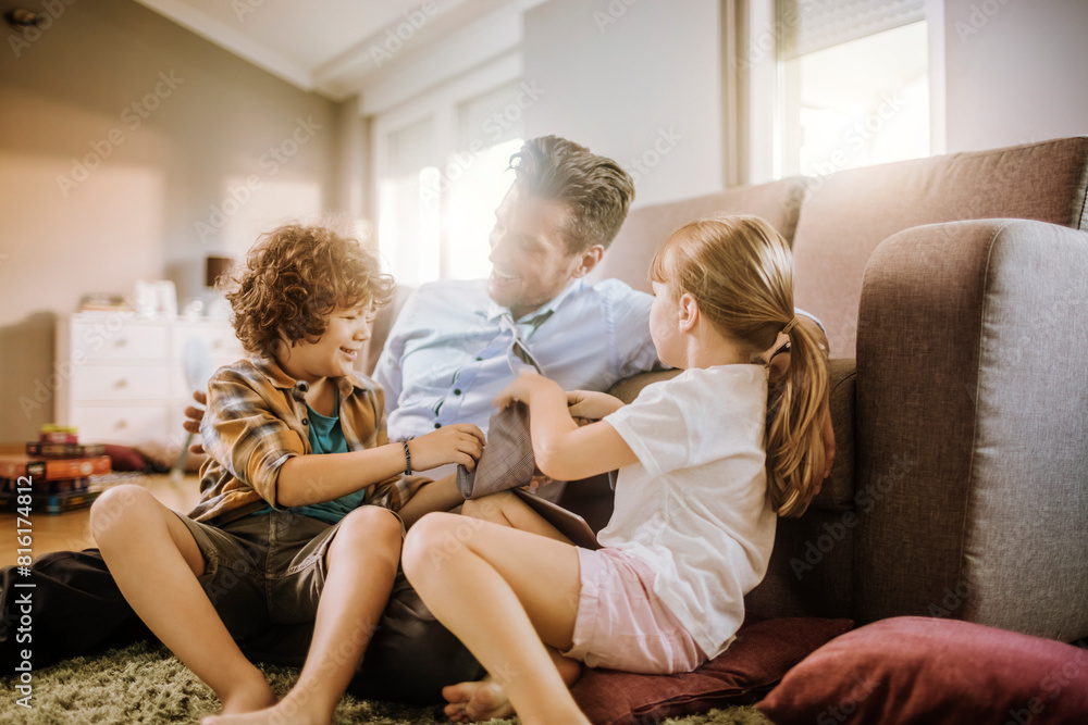 Happy father playing with son and daughter at home