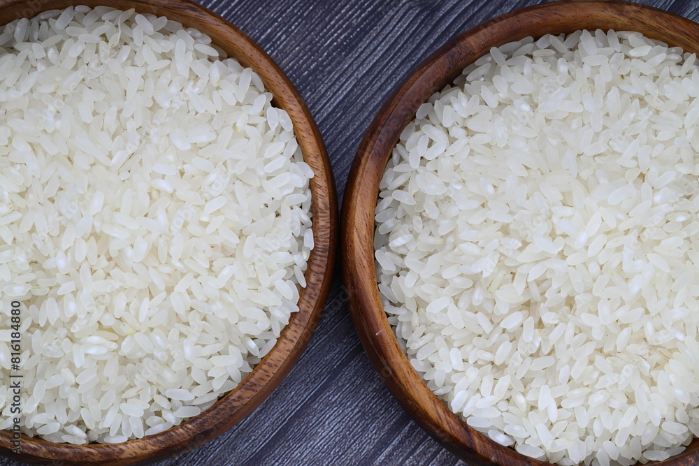 Raw white rice on wooden background. Long uncooked rice in wooden plate. Natural organic food. Traditional Asian cereal culture. Raw white rice on wooden background. Long uncooked rice in wooden plate. Natural organic food. Traditional Asian cereal culture.