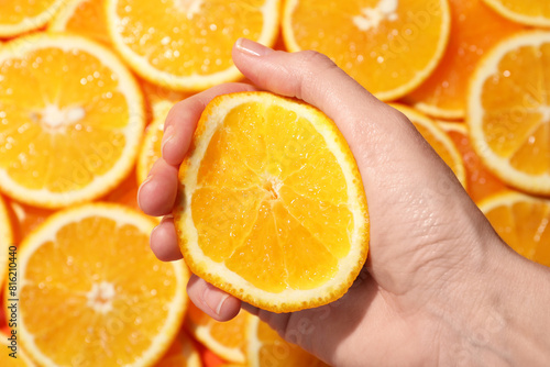 Woman squeezing juicy orange near slices of fruit, top view photo