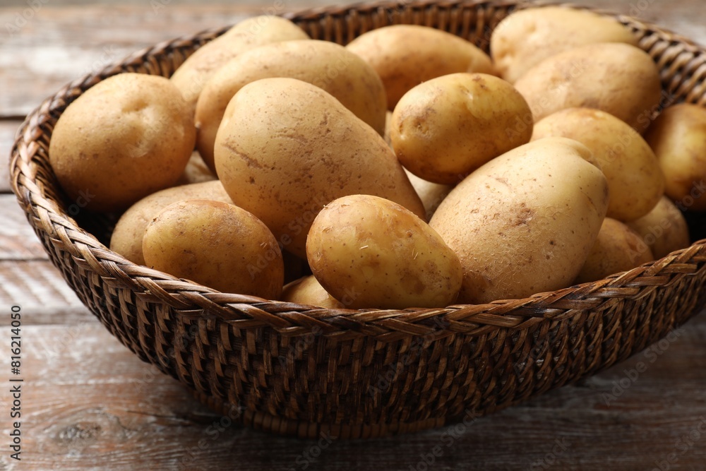 Raw fresh potatoes in wicker basket on wooden table, closeup Raw fresh potatoes in wicker basket on wooden table, closeup