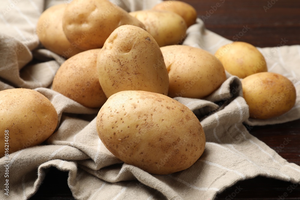 Raw fresh potatoes and napkin on wooden table, closeup Raw fresh potatoes and napkin on wooden table, closeup