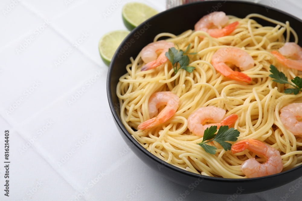 Tasty spaghetti with shrimps and parsley in bowl on light tiled table, closeup. Space for text Tasty spaghetti with shrimps and parsley in bowl on light tiled table, closeup. Space for text