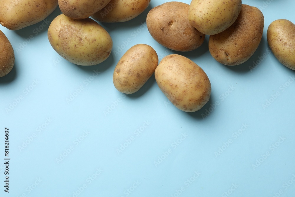 Many fresh potatoes on light blue background, flat lay. Space for text Many fresh potatoes on light blue background, flat lay. Space for text