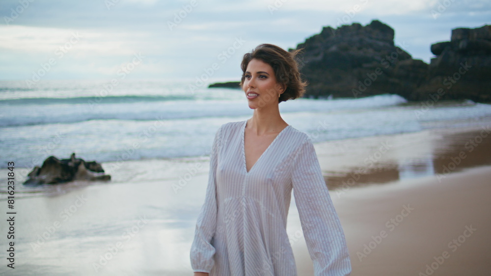 Beautiful brunette walking shore on cloudy day. Smiling lady enjoy summer coast