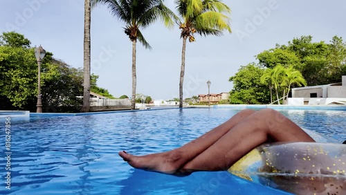 Young woman relaxing inside swimming pool at hotel during summer holiday vacations.