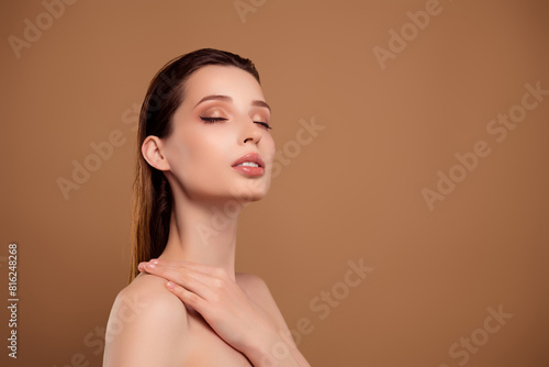 Photo of sweet adorable lady naked shoulders enjoying body lotion empty space isolated brown color background