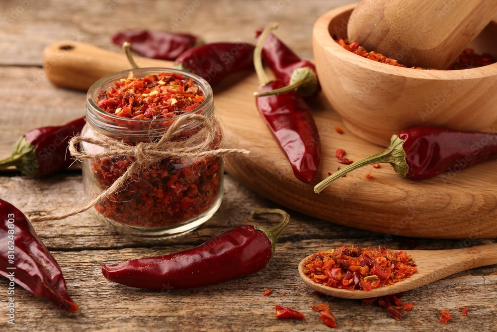 Chili pepper flakes and pods on wooden table, closeup Chili pepper flakes and pods on wooden table, closeup